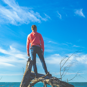 man smiling standing on a log