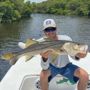man smiling and holding a snook on fishing charter