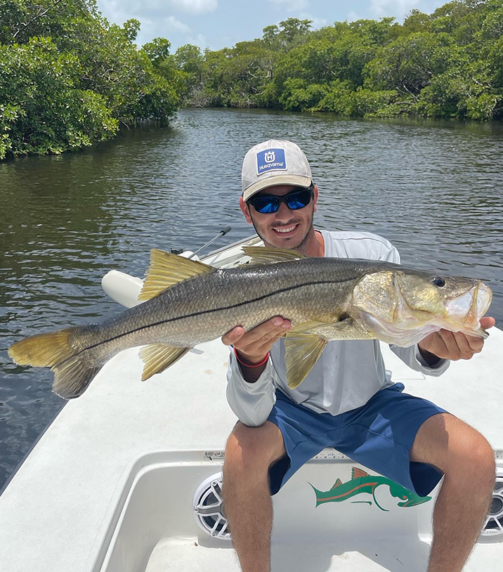 man smiling and holding a snook on fishing charter